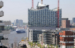 Neubauten am Grasbrookhafen in der Hafencity - entstehende Albphilharmonie mit Glasfassade - Frachtschiff auf der Elbe.