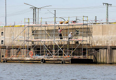 Ausbesserung der Kaimauer am Versmannkai im Hamburger Baakenhafen - schwimmender Ponton mit Baugerüst.