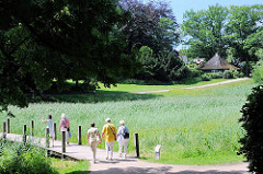 Spaziergängerinnen im Stadtpark Harburgs überqueren ein Feuchtbiotop über einen Steg im Harburger Stadttpark.