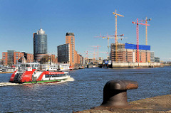 Bürogebäude am Kehrwieder - Baustelle der Elbphilharmonie (2009); eine Hafenfähre fährt zum Anleger Theater am Hafen - im Vordergrund ein Eisenpoller zum Vertauen von Schiffen.