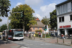 Linienbus 5 der HVV Richtung Hamburger Innenstadt / ZOB in der Frohmestrasse. Reetdachhaus und Geschäfte in der Schnelsener Hauptverkehrsstrasse.