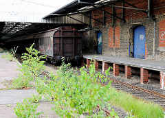 Ehem. Güterbahnhof Oberhafen - junge Birken wachsen auf dem Bahnsteig - Güterwaggons vor dem Klinkerlagergebäude in der Hafencity Hamburg.