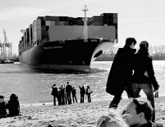 Das Containerschiff CMA CGM CARMEN läuft in den Hamburger Hafen ein - das Frachtschiff wendet auf der Elbe; Zuschauer am Elbstrand bei der Strandperle in Hamburg Othmarschen.