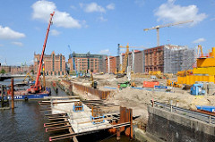 Bauarbeiten am Ufer des Magedburger Hafens in der Hamburger Hafencity - ein Kran auf einem Arbeitponton erledigt Rammarbeiten. Im Hintergrund des Gebäude des  Kaispeichers B, in dem das Maritime Museum seine Ausstellungsräume hat.