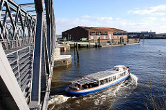 Barkasse unter der neugebauten Baakenbrücke - im Hintergrund ein Schiffsanleger mit Wassertreppe und Lagerschuppen am Baakenhafen.