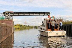 Geöffnetes Schleusentor der Krapphofschleuse am Schleusengraben von Hamburg Bergedorf - ein Sportboot verlässt die Schleusenkammer und fährt in den Schleusengraben ein.