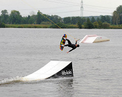 Absprungrampe der Wasserskianlage am Neuländer See - ein Wakeboarder springt ab - Bilder aus Hamburg Neuland.