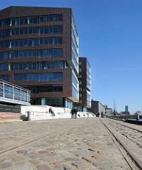 Modernes Bürogebäude, Kopfsteinpflaster und Schienen der alten Hafenbahn in Altona.