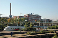 Zug im Harburger Bahnhof - Schornstein und Industriegebäude mit Schriftzug der Phoenix.