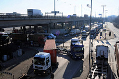 LKW mit Containern haben die Zollstation passiert und fahren in den Hamburger Freihafen ein. Darüber der Autoverkehr auf der Autobahn A7.