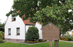 Geschnitztes Holzschild Siedlergemeinschaft AM RADELAND e.V. Die Eigenheimgemeinschaft entstand 1933 als Erwerbslosensiedlung.