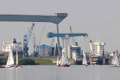 Segelschiffe vorm Estesperrwerk - Portalkran und Schiffsneubau der Sietas Werft.