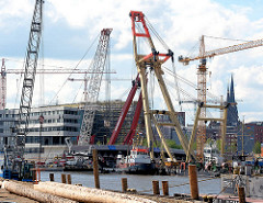 Schwimmkräne montieren ein Brückenteil der Baakenhafenbrücke am Versmannkai in der Hamburger Hafencity.
