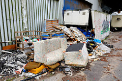 Wild abgeladener Müll am Strassenrand von Hamburg Wilhelmsburg - Couchgarnitur und Müllsäcke im aufgebrochenen Container.
