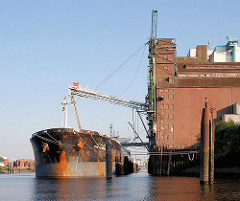 Die Ladung eines Massengutfrachters wird beim Rethespeicher gelöscht - die Sauganlage ragt aus dem Speichergebäude - Fotos aus dem Stadtteil Hamburg Wilhelmsburg.