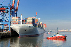 Zwei rote Schlepper ziehen den Containerfrachter NYK HELIOS von der Kaimauer des Containerterminals Altenwerder. Das 2013 gebaute Frachtschiff hat eine Länge von 365,50m und eine Breite von 48,40m; der Frachter kann 13208 TEU Container transportieren