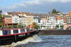 Die bunten Häuser an der St. Pauli Hafenstrasse - eine Barkasse mit Hamburg Fahne auf der Elbe.