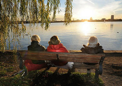 Herbst an der Alster - Hamburgerinnen geniessen die untergehende Sonne auf einer Bank an der Alster im Hamburger Stadtteil Uhlenhorst.
