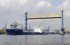 Angehobene Hubbrücke am Kattwykdamm - ein Frachtschiff hat fährt auf der Süderelbe - im Hintergrund die Containerkräne des Terminals Altenwerder.