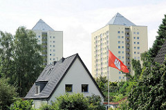 Einzelhaus mit Spitzdach und Hamburg Fahne im Vorgarten - im Hintergrund Hochhäuser von Hamburg Lohbrügge Nord - auf dem Dach befinden sich Fotovoltaikanlagen zur Energiegewinnung.