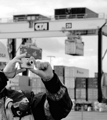 Arbeiterfotografie; Hafenarbeiter mit Kamera, Fotoapparat auf dem Container Terminal Altenwerder - im Hintergrund werden Container transportiert.