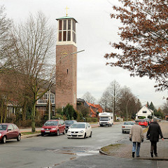 Kirchturm der St. Thomaskirche in Hamburg Hausbruch - Passanten, Spaziergänger auf dem Fussweg .