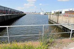 Blick vom Baakenkai in den Baakenhafen; ein Schiff liegt am Versmannkai - lks. der Petersenkai mit Lagerschuppen - im Hintergrund das Hamburg-Panorama mit den Kirchtürmen der Hansestadt.