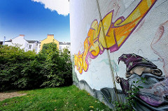 Graffiti an einer Hauswand - Wohnhäuser im Grünen.