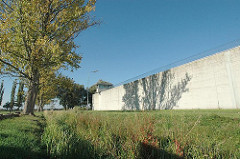 JVA Neuengamme - Gefängnismauer der Justizvollzugsanstalt - Jugendhaftanstalt. Gefängnismauer mit Wachturm und Stacheldraht. Die JVA befand sich auf dem Gelände des ehem. KZ Neuengamme.