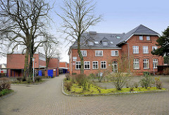 Altes Schulgebäude in Hamburg Hausbruch - erbaut 1896; Backsteinfassade - daneben Schulneubauten der 1960er Jahre.