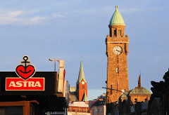Abendsonne am Hamburger Hafen - Werbung für Astrabier und der Uhrenturm der Landungsbrücken.