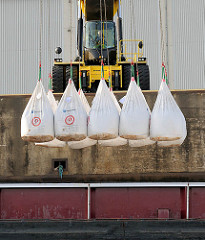 Säcke mit Schüttgut werden von einem Binnenschiff im Hamburger Hafenbezirk Steinwerder an Land gehievt.