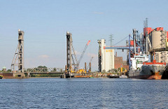 Blick über den Reiherstieghafen - rechts die Kaliumschlagsanlage; ein Frachtschiff hat am Kai festgemachte; in der Bildmitte die Rethehubbrücke, dahinter der Reiherstieg.