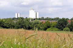 Weite Wiese in Hamburg Langenbek - hohes Gras und Bäume - Grünanlage im Stadtteil; im Hintergrund Hochhäuser von Hamburg Sinstorf.