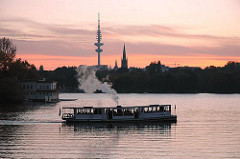 Sonnenuntergang an der Hamburge Alster - der historische Alsterdampfer St. Georg im Langen Zug - am Abendhimmel sind der Hamburger Fernsehturm zu erkennen.