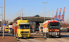 LKW haben die Zollgrenze und Zollstation des Hauptzollamt Waltershof durchfahren - im Hintergrund hochgefahrene Containerbrücken des Containerterminals Waltershof.