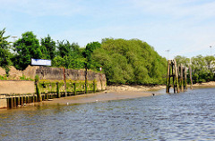 Kaimauer bei Niedrigwasser im Hamburger Hafen - der Bereich bei Hochwasser ist mit Algen bewachsen. Bei Ebbe zeigen sich die Baumstämme, die das Fundament der Kaianlage bilden.  Liegeplatz am Moldauhafen / Prager Ufer.