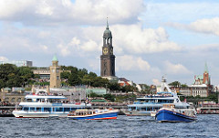 Barkassen und Fahrgastschiffe auf der Elbe vor den Hamburger St. Pauli Landungsbrücken - im Hintergrund der hohe Kirchturm des Hamburger Wahrszeichens, der Michel.