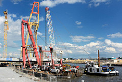 Schwimmkräne montieren ein Brückenteil der Baakenhafenbrücke am Versmannkai in der Hamburger Hafencity.