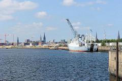 Ein Frachtschiff liegt am Versmannkai des Baakenhafens - im Hintergrund das Panorama der Hansestadt Hamburg.