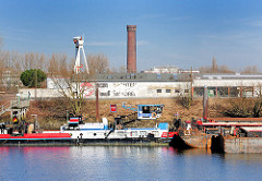 Blick über den Peutehafen - ein Schubschiff und Lastkähne, Schuten liegen am Ufer; im Hintergrund der historische Wasserturm in Hamburg Rothenburgsort auf der gegenüber liegenden Seite der Norderelbe.