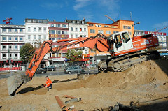 Bauarbeiten auf dem Spielbudenplatz - ein Bagger auf einem Sandhaufen, im Hintergrund Häuser an der Reeperbahn.