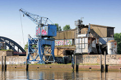Baustoffhandlung am Billehafen in Hamburg Rothenburgsort; Kran am Kai - Grafitti, im Hintergrund die Billhorner Brückenstrasse über den Oberhafenkanal.