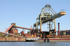 Ein Binnenschiff liegt mit einer Ladung Schrott im Hamburger Dradenauhafen - mit dem Kran und einem Schrottmagneten wird der Rohstoff an Land gebracht.