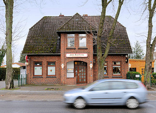 Kneipe Zum Dorfkrug - Backsteingebäude in der Neuwiedenthaler Strasse in Hamburg Hausbruch; fahrendes Auto.