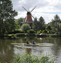 Wahrzeichen von Hamburg Reitbrook - Windmühle an der Dove Elbe - Ruderboot bei Trainingsfahrt.