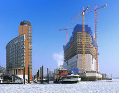 Baustelle der Elbphilharmonie im Winter - Entstehung der Hafencity - Bausstelle im Hamburger Hafen. Baukräne am Kaispeicher.