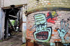 Industrieruine in Hamburger Stadtteil Wilhelmsburg - eine Ziegelmauer ist mit Grafitti besprüht.