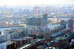 Blick über die Kupferdächer der Speicherstadt und den modernen Wohnhäusern am Sandtorkai zur entstehenden Elbphilharmonie - Fotos aus der Hamburger Hafencity.