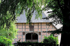 Fachwerkhaus mit Reet gedeckt zwischen Bäumen - historische Häuser in Hamburg Rönneburg.